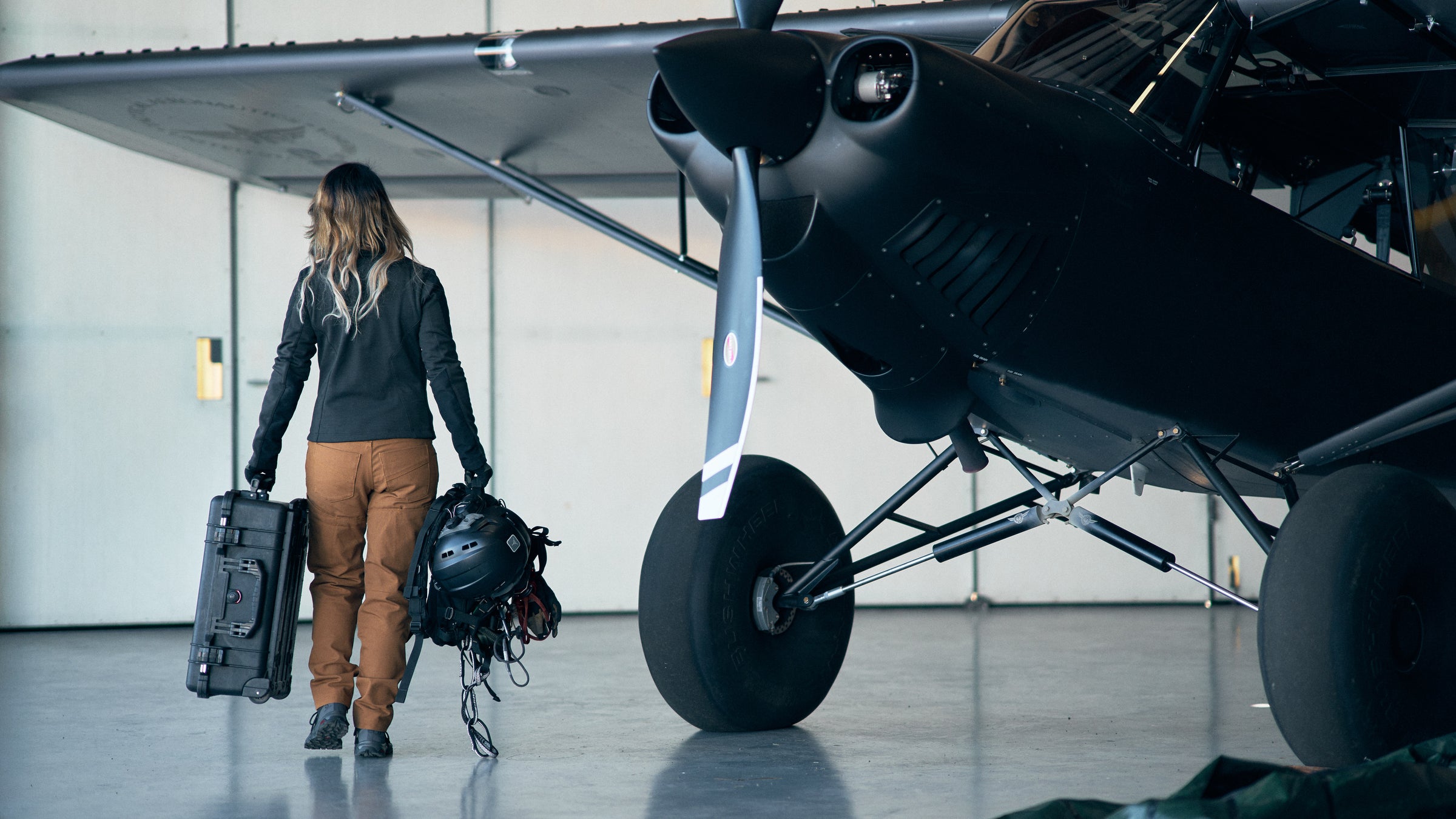 Pilot walking out to the aircraft with helmet case and gear
